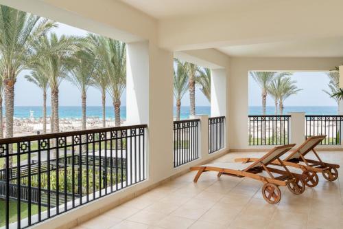 a balcony with a view of the beach and palm trees at JAZ Elite Crystal, Almaza Bay in Marsa Matruh
