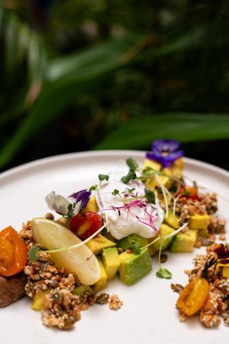 a white plate with a salad with vegetables and dressing at The Neela Boutique Hotel Stone Town in Zanzibar City