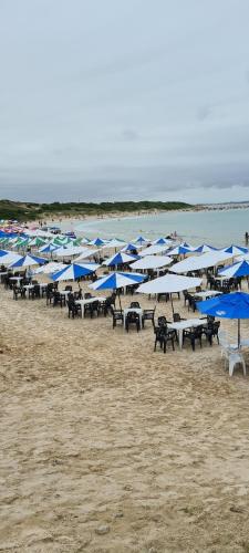 a group of tables and umbrellas on a beach at Red Rose in Cabo Frio