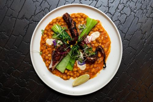 a plate of food with beans and vegetables on a table at The Neela Boutique Hotel Stone Town in Zanzibar City