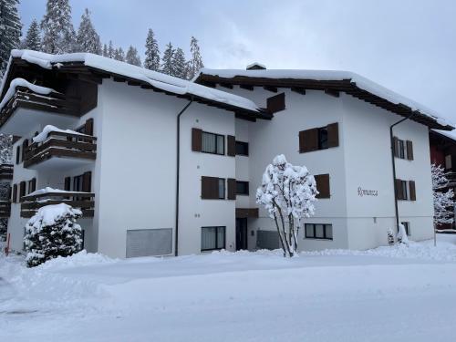 a building covered in snow with a tree in front at Mountain View Studio Klosters in Klosters