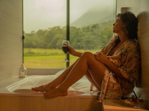 大普拉亞的住宿－Chalé Marrocos com Hidromassagem Pousada Índios Coroados，坐在窗户上拿着一杯葡萄酒的女人