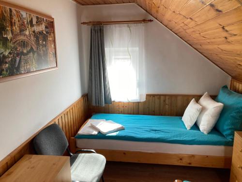 ティサケーチケにあるTünde Vendégházの青いベッドと窓が備わる小さな客室です。