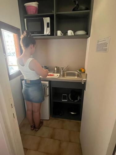 a woman standing in a kitchen preparing food at Hôtel & Résidence Le Subrini in Porto Ota