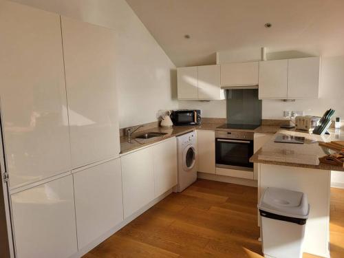 a kitchen with white cabinets and a sink and a dishwasher at Aquavista Penthouse in Wyke Regis