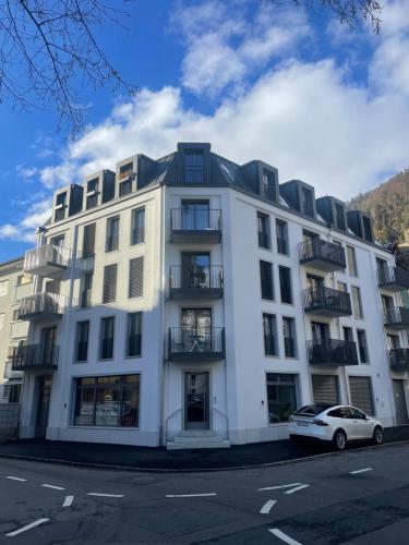 a white building with a car parked in front of it at Modern City Apartments in Interlaken