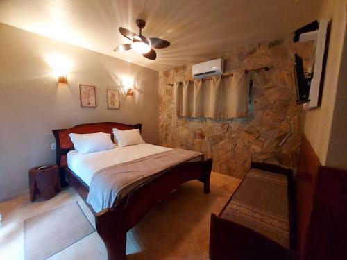 1 dormitorio con cama y pared de piedra en Salto Corumbá Hotel Camping Clube, en Corumbá de Goiás