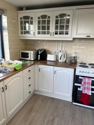 a kitchen with white cabinets and white appliances at An Cnoc in Killorglin