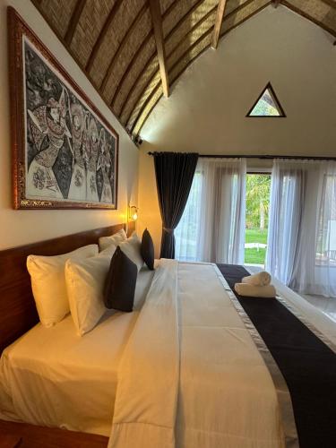 een groot wit bed in een kamer met een raam bij The Dulu Penida Cottage in Nusa Penida