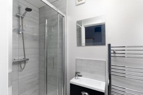 a white bathroom with a shower and a sink at Large newly refurbished modern house, part sea views, south facing garden, parking in Penzance