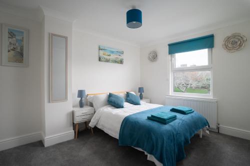 a bedroom with a bed with blue sheets and a window at Large newly refurbished modern house, part sea views, south facing garden, parking in Penzance