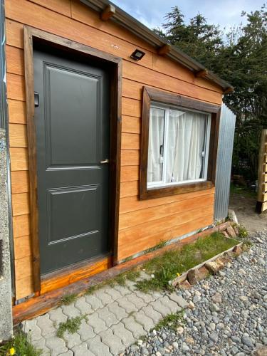 a tiny house with a black door and a window at Rufa’S in El Chalten