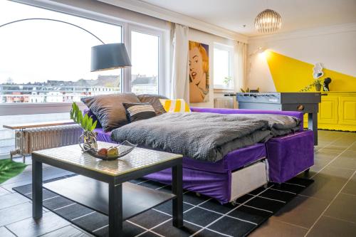 1 dormitorio con cama morada y mesa en Pop Art Loft über den Dächern von Koblenz en Koblenz