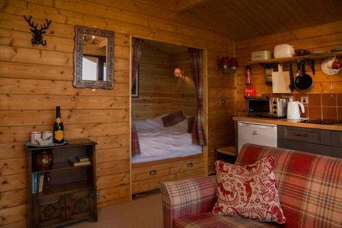 a living room with a bed in a log cabin at Cedarwood, an intimate and romantic cabin for two. in Icklesham