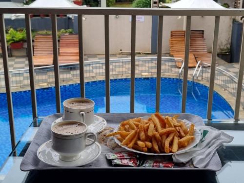 a tray with a plate of french fries and two cups of coffee at Sriniketana Homestay in Madikeri