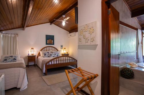 a bedroom with two beds and a bathroom with a tub at Pousada Recanto do Arraial in Arraial d'Ajuda