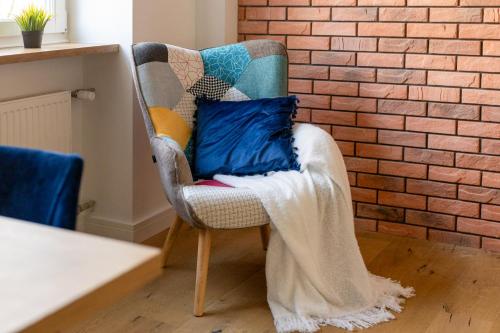 a chair with a blanket sitting next to a brick wall at Koźla Warsaw Old Town 1-Bedroom Superior Apartment WWA54 in Warsaw
