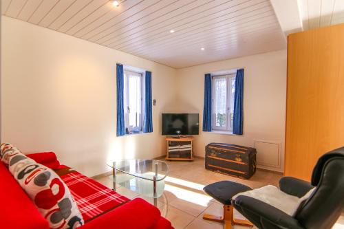 a living room with a red couch and a tv at Paultina by Arosa Holiday in Arosa