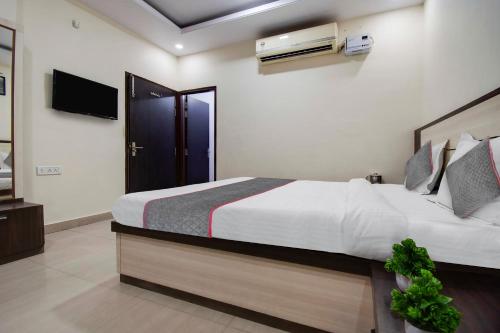 een slaapkamer met een groot bed en een televisie bij Capital O Hotel Pink Peral in Jaipur