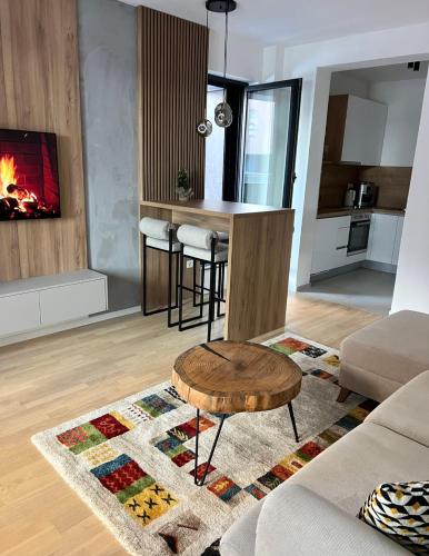 a living room with a table and a fireplace at Arbor Apartment in Bjelašnica