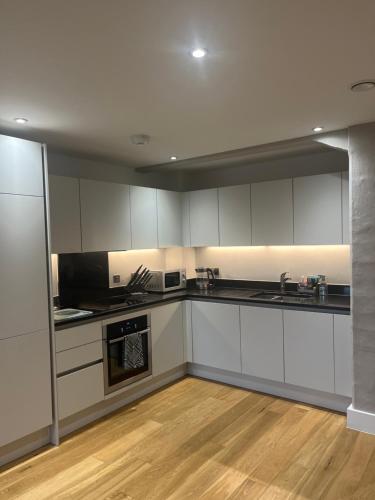 a kitchen with white cabinets and a wooden floor at Huller and cheese warehouse apartments in Bristol