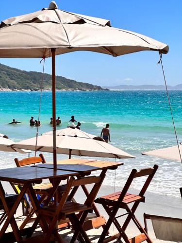 a table and chairs with an umbrella on the beach at Pousada Seven in Arraial do Cabo