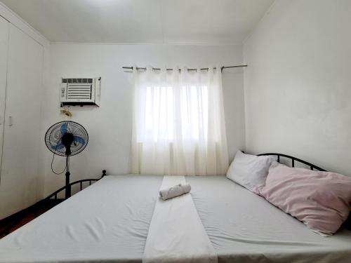 um quarto com uma cama, uma ventoinha e uma janela em Calapan Transient Molave L48 em Calapan