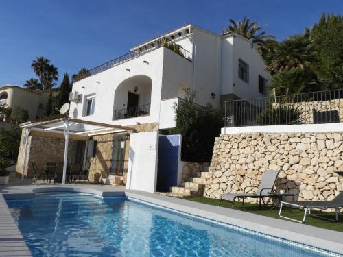 eine Villa mit einem Pool vor einem Haus in der Unterkunft Casa Andamar in Benissa