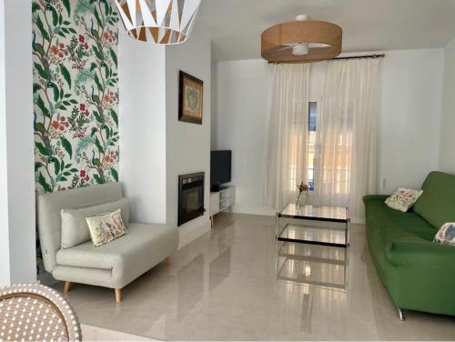 a living room with a green couch and a chair at Casa Muralla del Alcazar Viejo in Córdoba