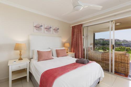 a bedroom with a bed and a large window at Laguna La Crete 34 in Uvongo Beach