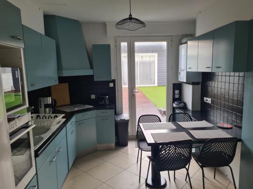 une cuisine avec des armoires bleues et une table et des chaises dans l'établissement Opal'In, à Gravelines
