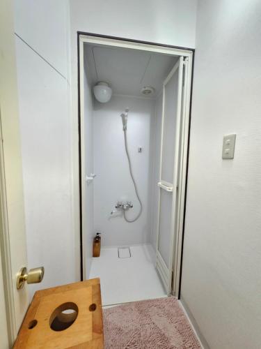 a bathroom with a shower in a white room at guest house White House ホワイト ハウス in Shimukappu