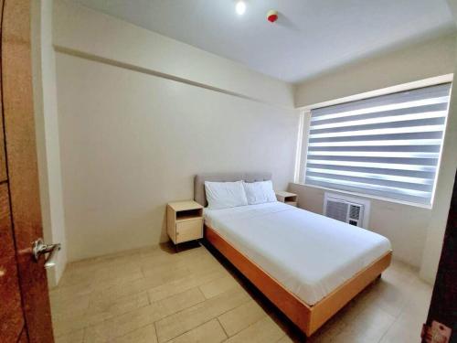 ein Schlafzimmer mit einem weißen Bett und einem Fenster in der Unterkunft Condo in Pasay in Manila