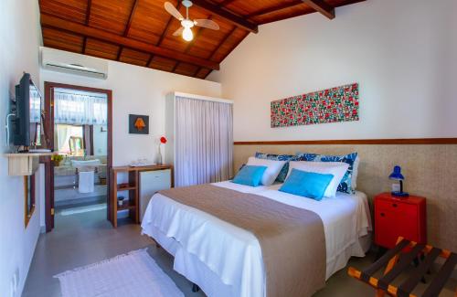 a bedroom with a bed with blue pillows and a television at Pousada Recanto do Arraial in Arraial d'Ajuda