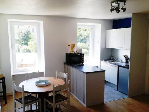 une cuisine avec une petite table et des placards blancs dans l'établissement Petit appartement proche de la gare, à Brest