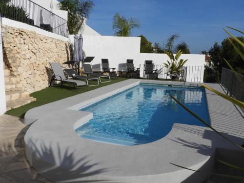 ein Pool in einem Garten mit Stühlen um ihn herum in der Unterkunft Casa Andamar in Benissa