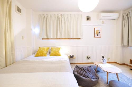 a bedroom with a bed with yellow pillows and a table at 夢の舎 浅草 Yumenoya Asakusa in Tokyo