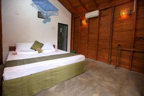 a bedroom with a large bed with wooden walls at The Mastodon Valley Safari Resort in Udawalawe