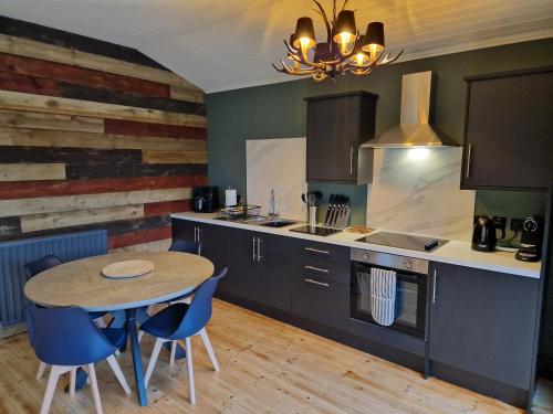 cocina con mesa y sillas azules en Hunters Glebe Lodge, en Castlerock