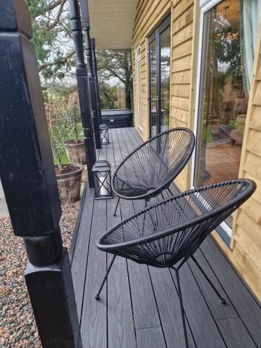 two chairs sitting on a wooden deck at Hunters Glebe Lodge in Castlerock