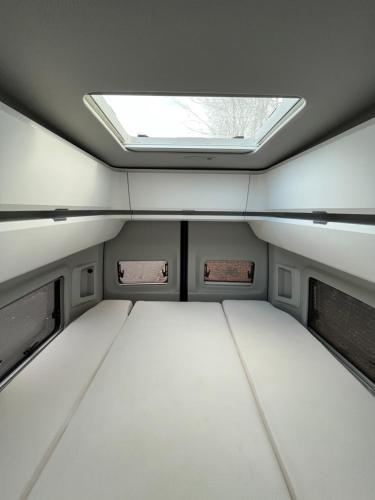 a small bed in a trailer with a skylight at Löwen Unterkunft Braunschweig in Braunschweig