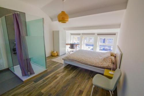 ein Schlafzimmer mit einem Bett und einem Stuhl in der Unterkunft Residence Royal Sélys Terrace, City-Center - Bike Park in Lüttich