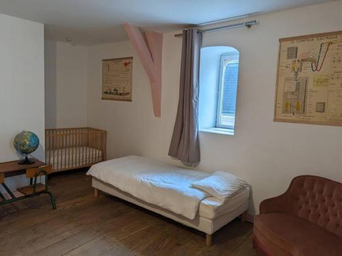 een slaapkamer met een bed, een raam en een bank bij Le Logis de Louis in Saint-Savin