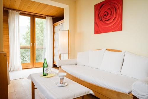 a living room with a white couch and a red rose at Panoramahotel Wagner - Das Biohotel am Semmering in Semmering