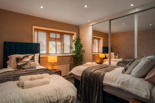 a bedroom with two beds and a large mirror at Airport Haven: Pool Table, Games Room, Sleeps 9 in Thorley