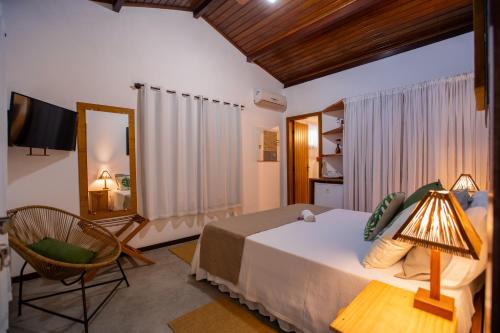 a bedroom with a bed and a mirror and a chair at Pousada Recanto do Arraial in Arraial d'Ajuda