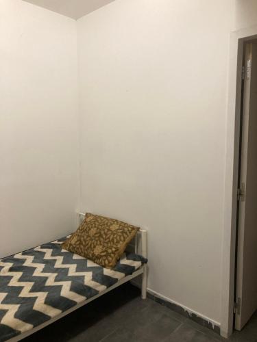 Cama pequeña en habitación con pared blanca en Hostel auberge en Béziers