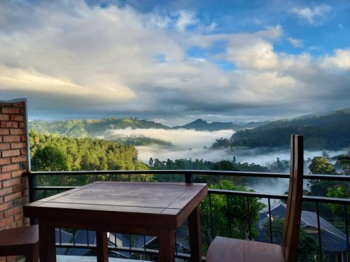 a table on a balcony with a view of a foggy valley at Nine Arch Gap in Ella