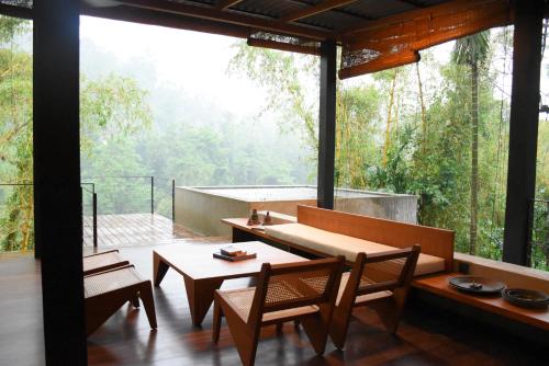Yatiyantota的住宿－River Pavilion, Kitulgala，客房设有桌椅和大窗户。