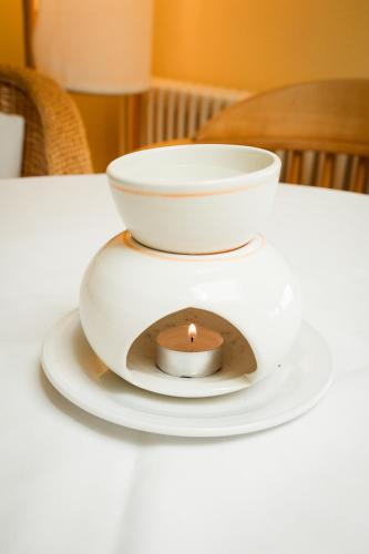 a candle on a white plate on a table at Panoramahotel Wagner - Das Biohotel am Semmering in Semmering